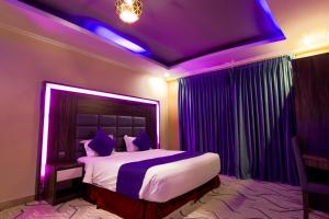 达曼Maskan Al Dyafah Hotel Apartments 2的一间卧室配有一张紫色照明的大床