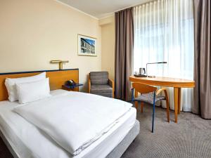 杜塞尔多夫杜塞尔多夫市中心美居酒店的配有一张床和一张书桌的酒店客房