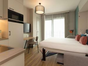 安特卫普Aparthotel Adagio Antwerp City Center的一间卧室配有一张床、一张书桌和一台电视