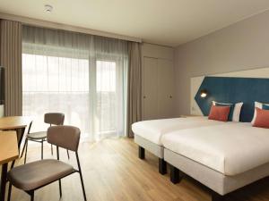 安特卫普Adagio Antwerp City Center的酒店客房设有一张大床和一张书桌。