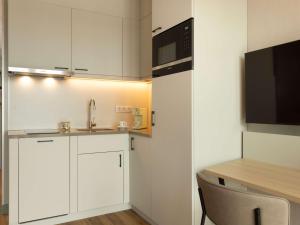 安特卫普Adagio Antwerp City Center的厨房配有白色橱柜、水槽和微波炉