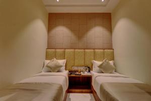 孟买Hotel Amber Suite Near Mumbai Airport的客房设有两张床和一张桌子及电话