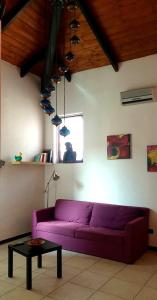 雷焦卡拉布里亚La Casita的客厅配有一张紫色沙发,配有一张桌子