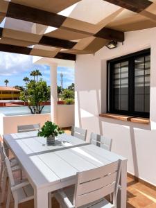科拉雷侯Laguna Home by Best Holidays Fuerteventura的庭院配有白色的桌椅,设有窗户