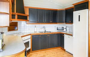 MidsundNice Home In Midsund With Kitchen的厨房配有黑色橱柜和白色冰箱。