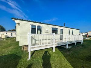 大雅茅斯8 Berth Caravan With Decking At California Cliffs Near Scratby Beach Ref 50019f的站在白色房子前面的女人