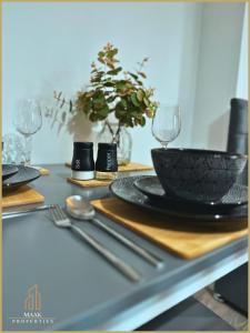 曼海德Minehead Suite的一张桌子,上面放着黑碗,盘子和银器