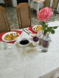 LyubintsyВілла Сади Єви的一张桌子,上面放着盘子和粉红色的玫瑰