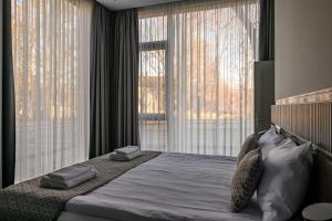 利耶帕亚Roze Peldu Residence的一间卧室设有一张大床和两个大窗户