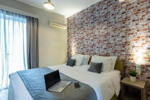 约阿尼纳Nantin Hotel Ioannina的一间卧室设有砖墙和一张带笔记本电脑的床