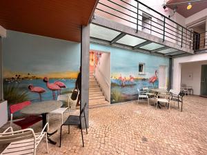 法鲁Albergaria Formosa的配有桌椅和火烈鸟壁画的房间
