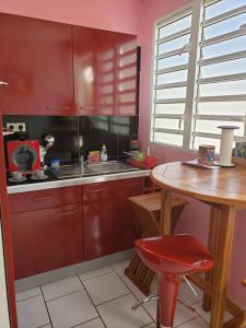 黑角ptit coin hibiscus的厨房配有红色橱柜和木桌