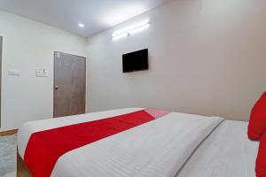 海得拉巴OYO Flagship Hotel Lavish Stay的白色卧室设有红色和白色的床和电视。