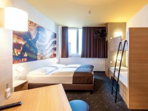 拜罗伊特B&B Hotel Bayreuth的酒店客房配有两张床和一张书桌