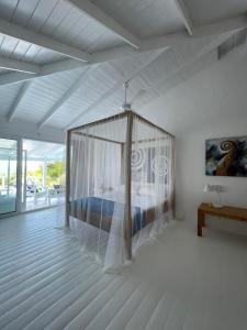 拉斯特拉纳斯ITAKA LOMA BONITA的一间白色客房内的卧室,配有一张天蓬床