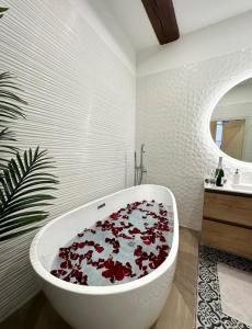 马孔Le Lamartine - vue Saône - Baignoire îlot的浴室设有装满红色鲜花的白色浴缸