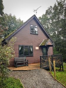 卡马森PrancingHare Lodge-Woodland Lodges-Pembrokshire的小木屋,甲板上设有长凳