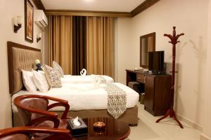 安曼Grape Village Hotel的酒店客房设有床、桌子和电视。