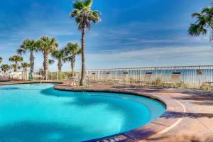 巴拿马城海滩Splash Beach Resort by Panhandle Getaways的围栏前的棕榈树游泳池