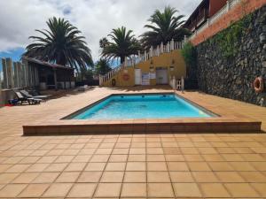 下布雷尼亚Lourdes 1 casa compartida solo con la anfitriona的棕榈树建筑旁边的游泳池