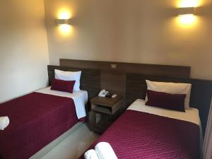普雷图河畔圣若泽伊皮中心酒店的两张位于酒店客房的床,配有红色和白色床单