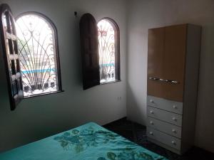 马瑙斯Casa grande em área central, bem iluminada e vent.的一间卧室设有2扇窗户、1张床和1个梳妆台。