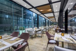 波哥大波哥大机场万怡酒店的餐厅设有桌椅和大窗户。