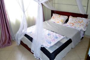 Njeruolive Palm Suites的一间卧室配有一张带天蓬的床