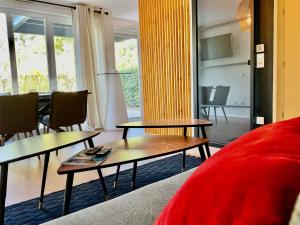 奥贝奈Le Safran的客厅配有两张桌子和一张红色沙发