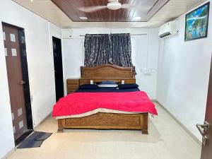 达曼Chirag Banglow 2BHK的一间卧室配有一张带红色毯子的木床