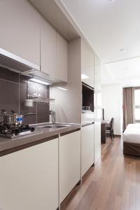 首尔江南城市广场酒店的一间厨房,配有白色的橱柜和一张位于客房内的床