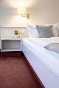 巴德贝芬森Hotel Ilmenautal inklusive THERMEplus的卧室配有一张白色大床和一张边桌