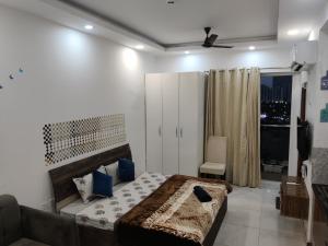 诺伊达The Forest Stays-Luxury Studio Apartment In Noida的一间卧室配有一张带蓝色枕头的床和一扇窗户。