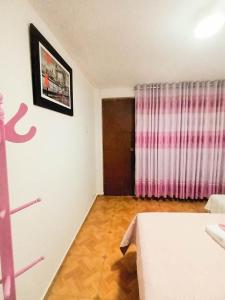 利马Female Accommodation Experience in front of Lima Airport的配有床和粉红色窗帘的房间