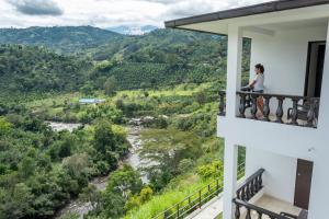 圣奥古斯丁Hotel Campestre El Triunfo的站在一个眺望着河流的阳台上的女人