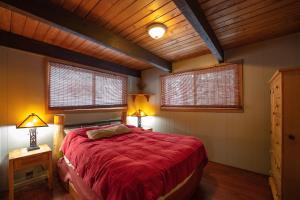 莱文沃思Leavenworth Mountain View Cabin w/ Space to Hike的一间卧室配有一张红色的床、两盏灯和两扇窗户