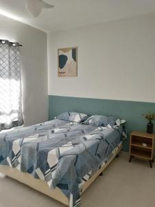 埃斯坦西亚Apartamento no Condomínio Vila das Águas的卧室内的一张带蓝色和白色棉被的床
