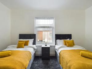 特伦特河畔斯托克Cliff House By RMR Accommodations - NEW - Sleeps 8 - Modern - Parking的配有两张床铺的黄色床单和窗户