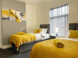 特伦特河畔斯托克Cliff House By RMR Accommodations - NEW - Sleeps 8 - Modern - Parking的黄色毯子的客房内的两张床