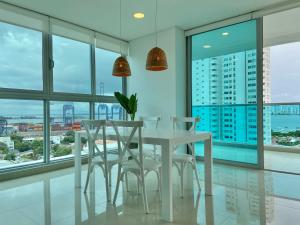 卡塔赫纳Wynwood Las Flores in Cartagena的一间设有白色桌子、椅子和窗户的用餐室