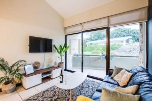 圣安娜CR MARIPOSA RENTALS Comfortable penthouse, AC, pool, gym, tennis的客厅配有蓝色的沙发和电视