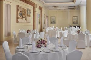 麦地那InterContinental Dar Al Iman Madinah, an IHG Hotel的宴会厅配有白色的桌椅和鲜花