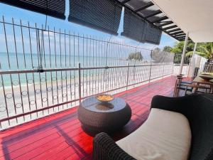 丹绒武雅Private Beach-front Haven by StayCo - Seaview Pool, KTV & Speaker System, Beach Air Loft, Private Beach Access and Beyond!的阳台配有桌子,享有海滩美景