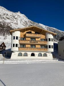 加尔蒂Garni Apart Wallamotta Silvretta Card Premium Betrieb的山前雪中建筑物