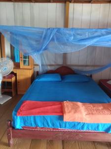KododaLestari Cottages的一间卧室配有一张蓝色天蓬床