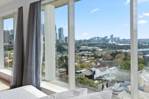 悉尼Holiday Inn Sydney Potts Point的一间带大窗户的卧室,享有城市美景