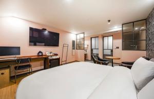 釜山Brown Dot Hotel Daeyeon的酒店客房设有一张床、一张书桌和一台电视机。