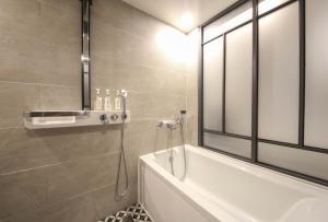釜山Brown Dot Hotel Daeyeon的一间带浴缸和淋浴的浴室,并设有一个窗户