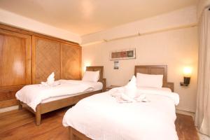 长滩岛Mayumi Beach Villa的一间设有两张带白色床单的床的房间