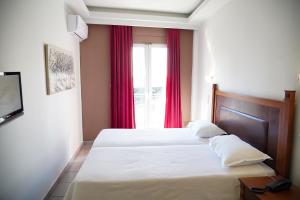 阿格里尼翁Hotel Selini的一间卧室设有两张床,窗户配有红色窗帘
